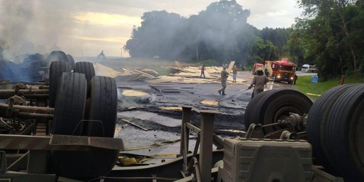 Caminhão carregado com madeira tomba e pega fogo na BR-476, na Lapa