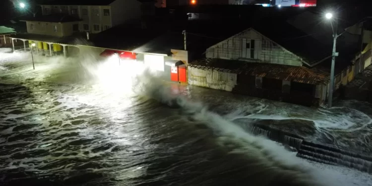 Maré cobre faixa de areia e invade calçada e imóveis, em Matinhos